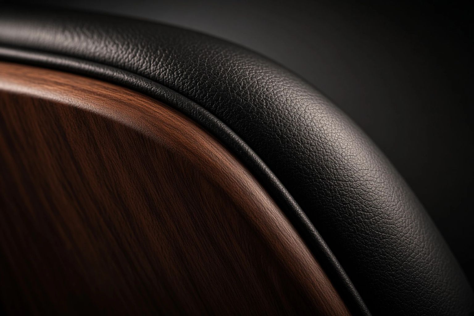 Macro crop of the chair's rolled leather edge meeting its walnut shell